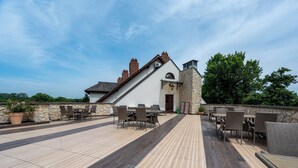 A rooftop patio with outdoor seating and a stone wall. - Sarmata (Sandomierz)