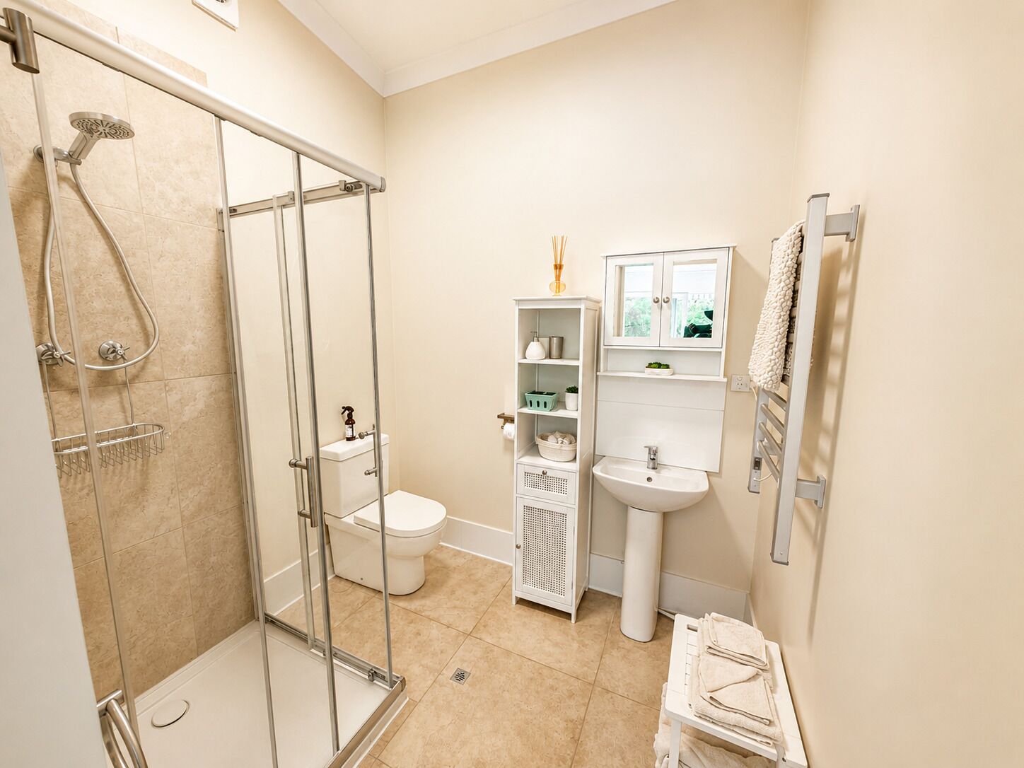Une salle de bain avec une douche à parois de verre, des toilettes, un lavabo et un meuble-lavabo avec des étagères.