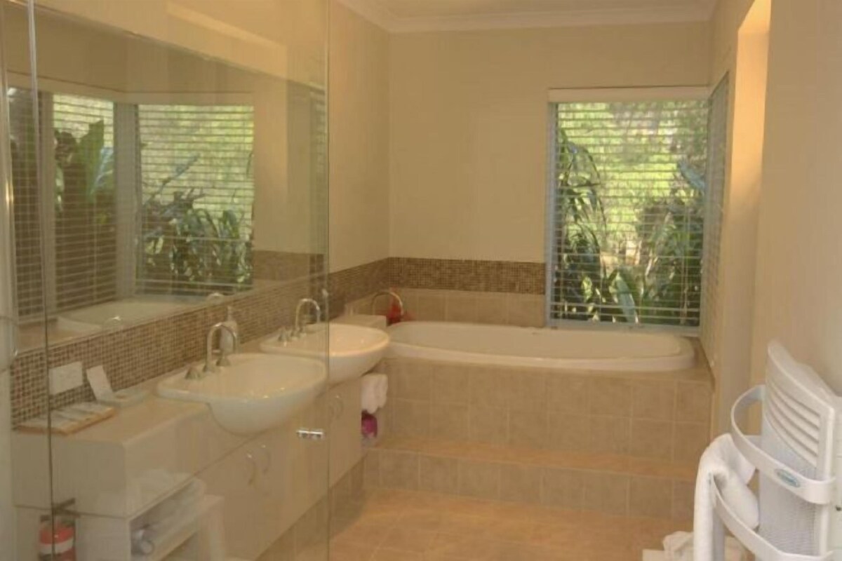 Un baño con lavamanos doble, bañera y cabina de ducha de vidrio.