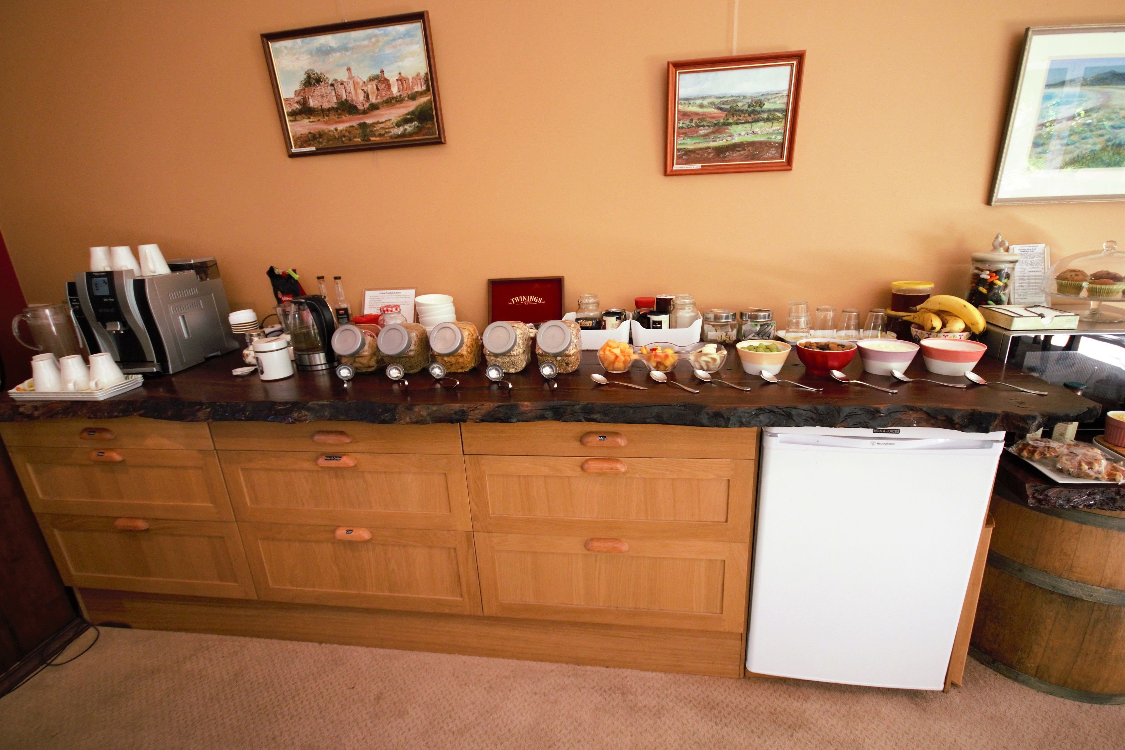 Una encimera de cocina con diferentes alimentos, una máquina de café y un refrigerador.