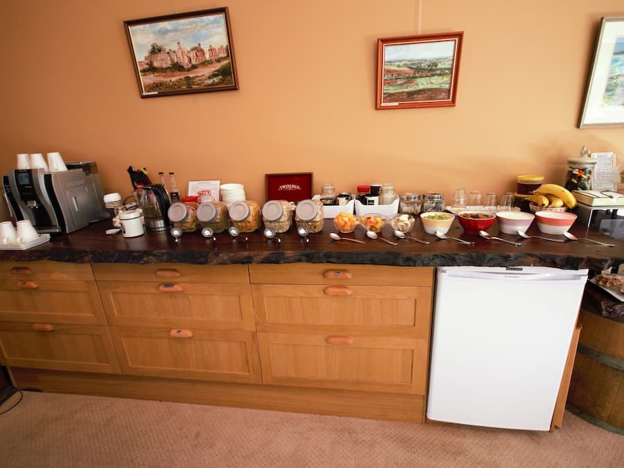 Una encimera de cocina con diferentes alimentos, una máquina de café y un refrigerador.