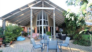 An outdoor patio with a covered seating area, a table with chairs, and potted plants.