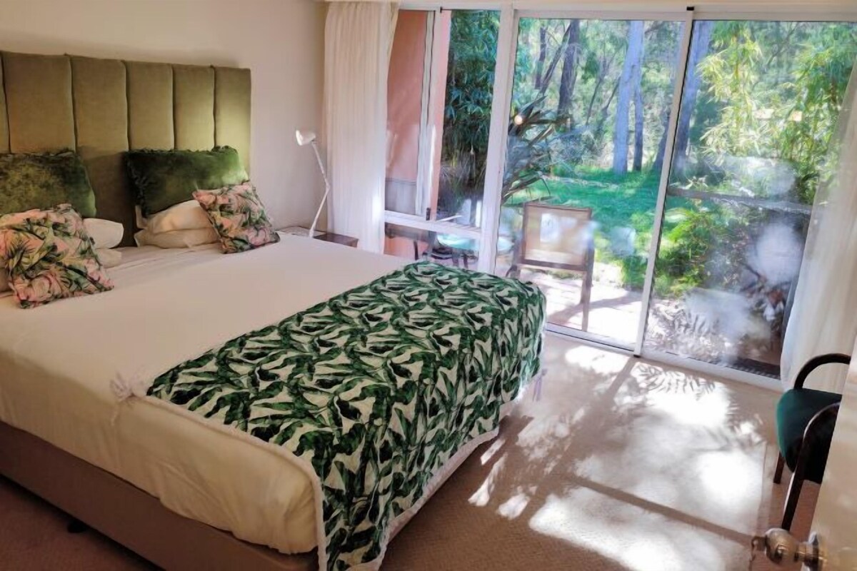 A bedroom with a bed, a headboard, a window, and a view of the outdoors.