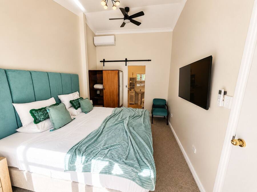 A bedroom with a bed, a ceiling fan, a TV, and a wardrobe.
