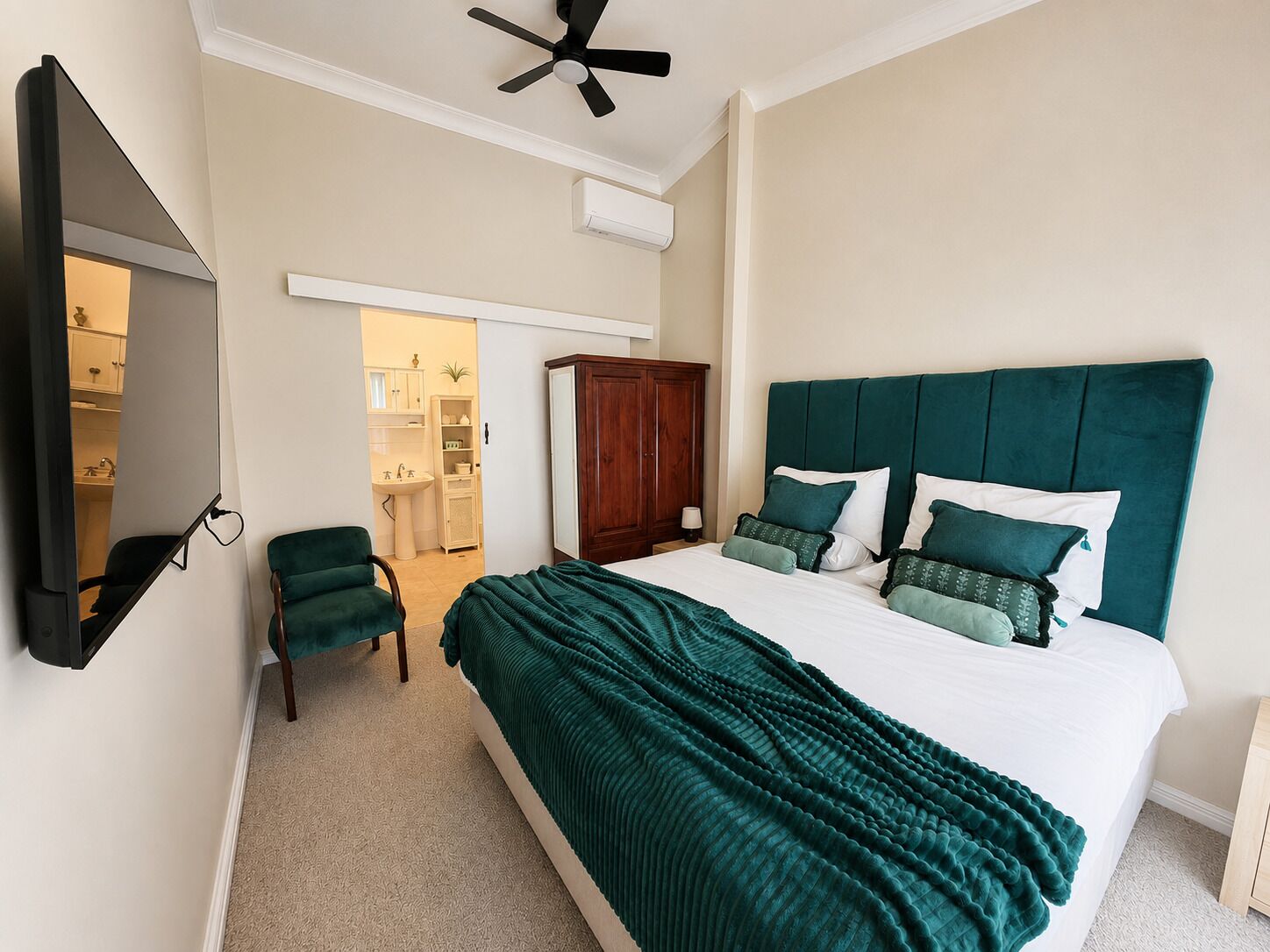A bedroom with a bed, a chair, a wardrobe, and a ceiling fan.