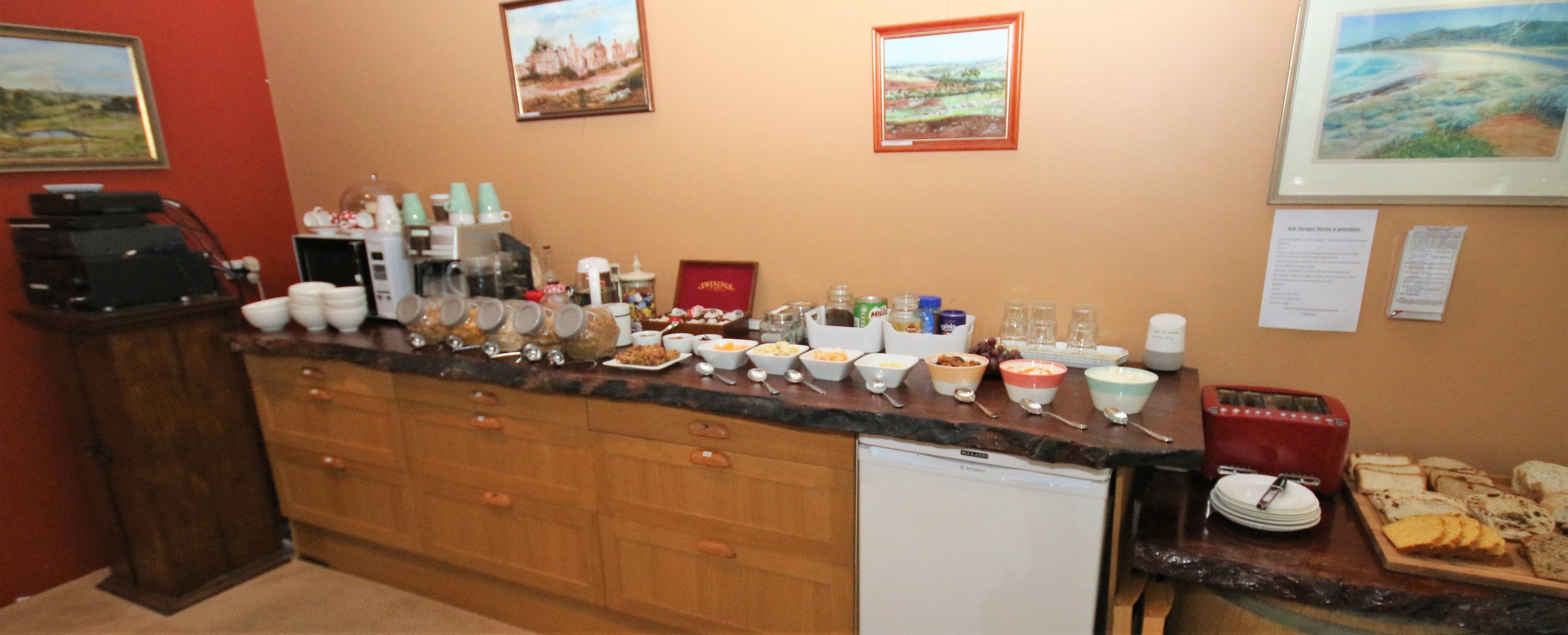 Cuina amb un taulell llarg, diferents bols i tasses, i una màquina de cafè.