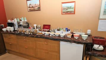 Cuina amb un taulell llarg, diferents bols i tasses, i una màquina de cafè.