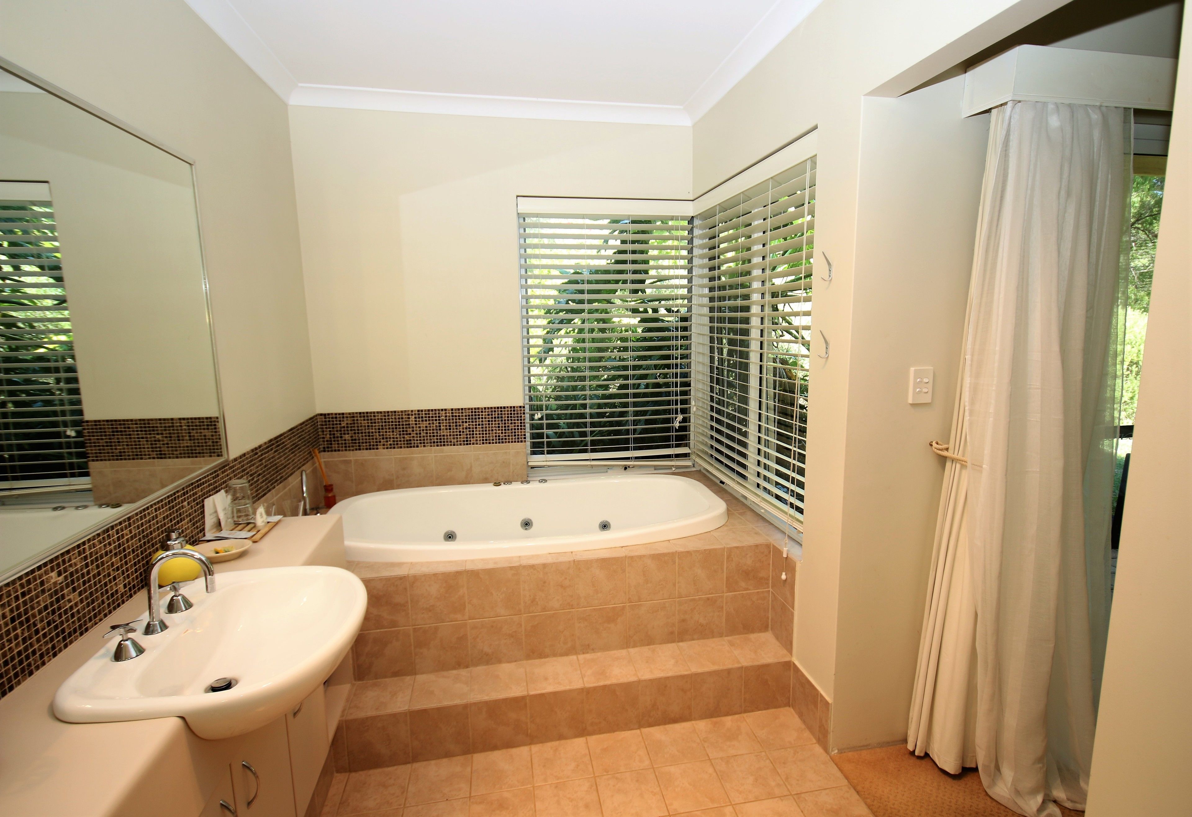 A bathroom with a bathtub, sink, and large mirror.