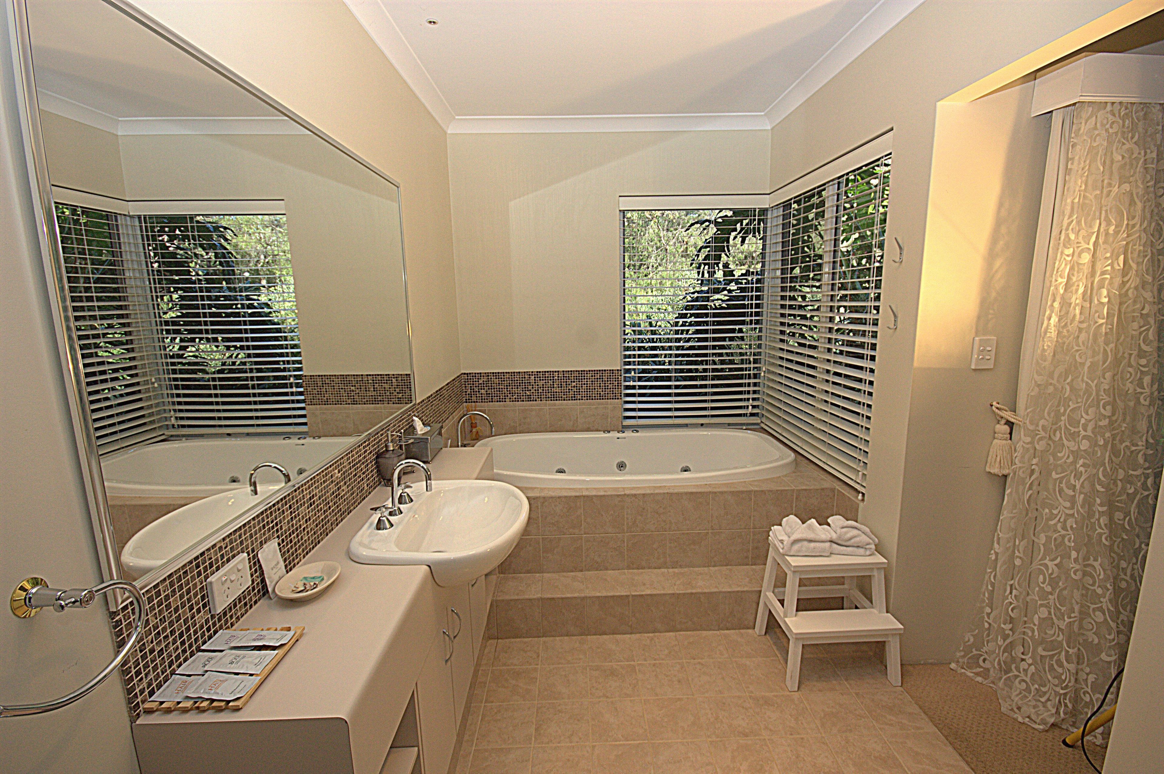 A modern bathroom with a double sink, a large bathtub, and a shower area.