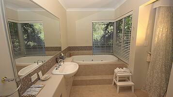 A modern bathroom with a double sink, a large bathtub, and a shower area.