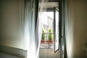 An open door to a balcony with a view of buildings and a potted plant. - Milanosuites (Milan)