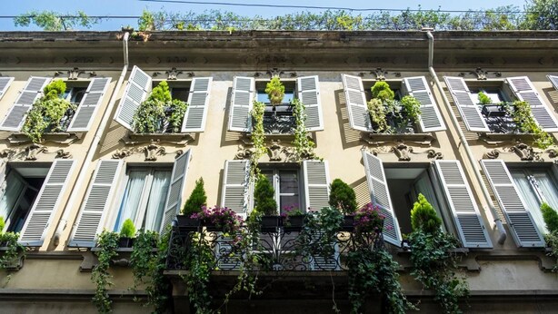 A building with multiple windows, some with shutters, and balconies with plants. - Milanosuites (Milan)