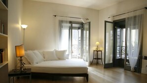 A bedroom with a bed, a bedside table with a lamp, a bookshelf, and a balcony with a railing. - Milanosuites (Milan)
