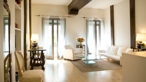 A modern living room with a glass coffee table, white sofas, and a wooden chair. - Milanosuites (Milan)