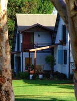 Una casa de dos pisos con porche, un jardín pequeño y una cerca de madera.