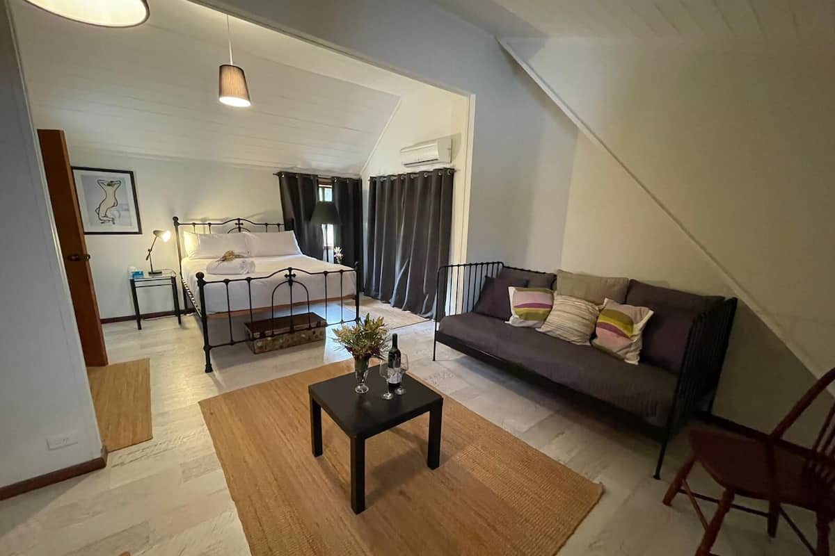 A spacious living area with a bed, a sofa, a coffee table, and a chair.