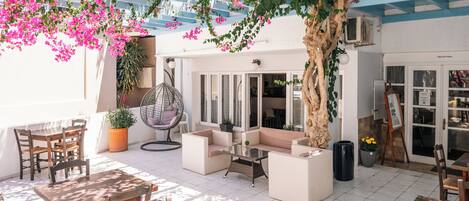 A sunlit patio with a seating area, a hanging chair, and a reception desk.