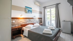 Un dormitorio con cama, mesitas de noche, aire acondicionado en la pared, ventana con cortinas y un balcón pequeño.