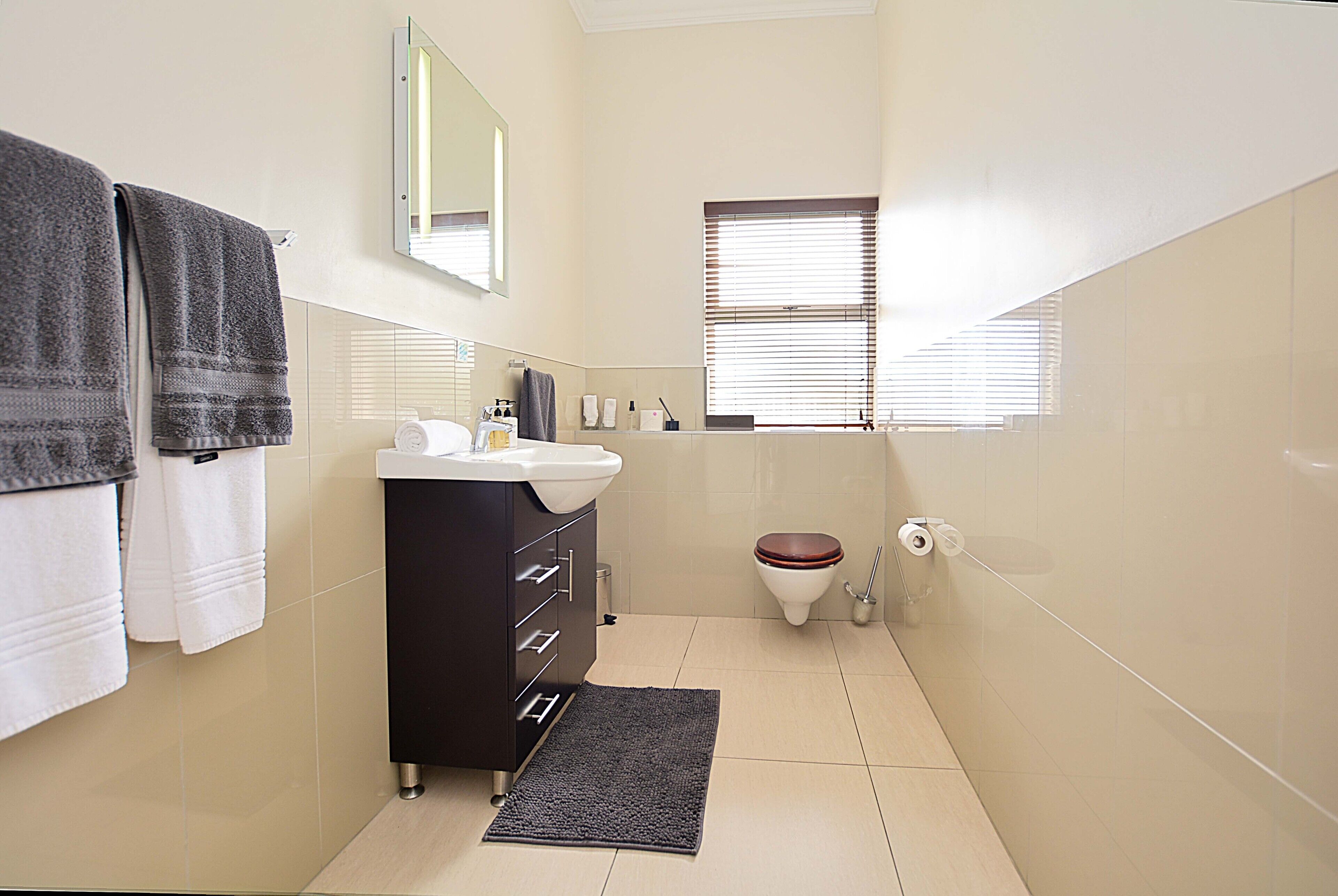 Ein kleines Badezimmer mit Waschbecken, Spiegel, Toilette und Fenster.
