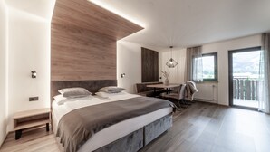 Ein modernes Schlafzimmer mit einem großen Bett, einem Schreibtisch und einem Balkon mit Aussicht.