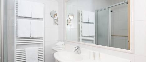 A modern bathroom with a white sink, a large mirror, and a glass shower enclosure.