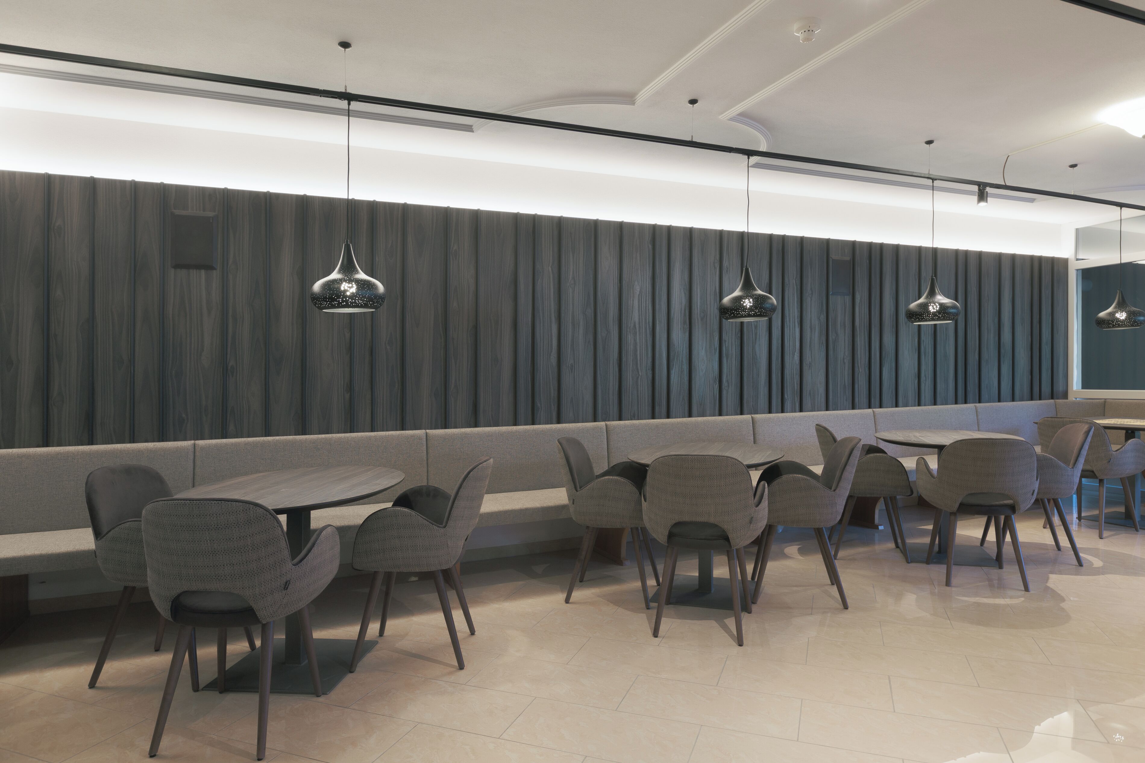 A modern restaurant with a long counter, multiple seating options including booths and tables, and pendant lighting.