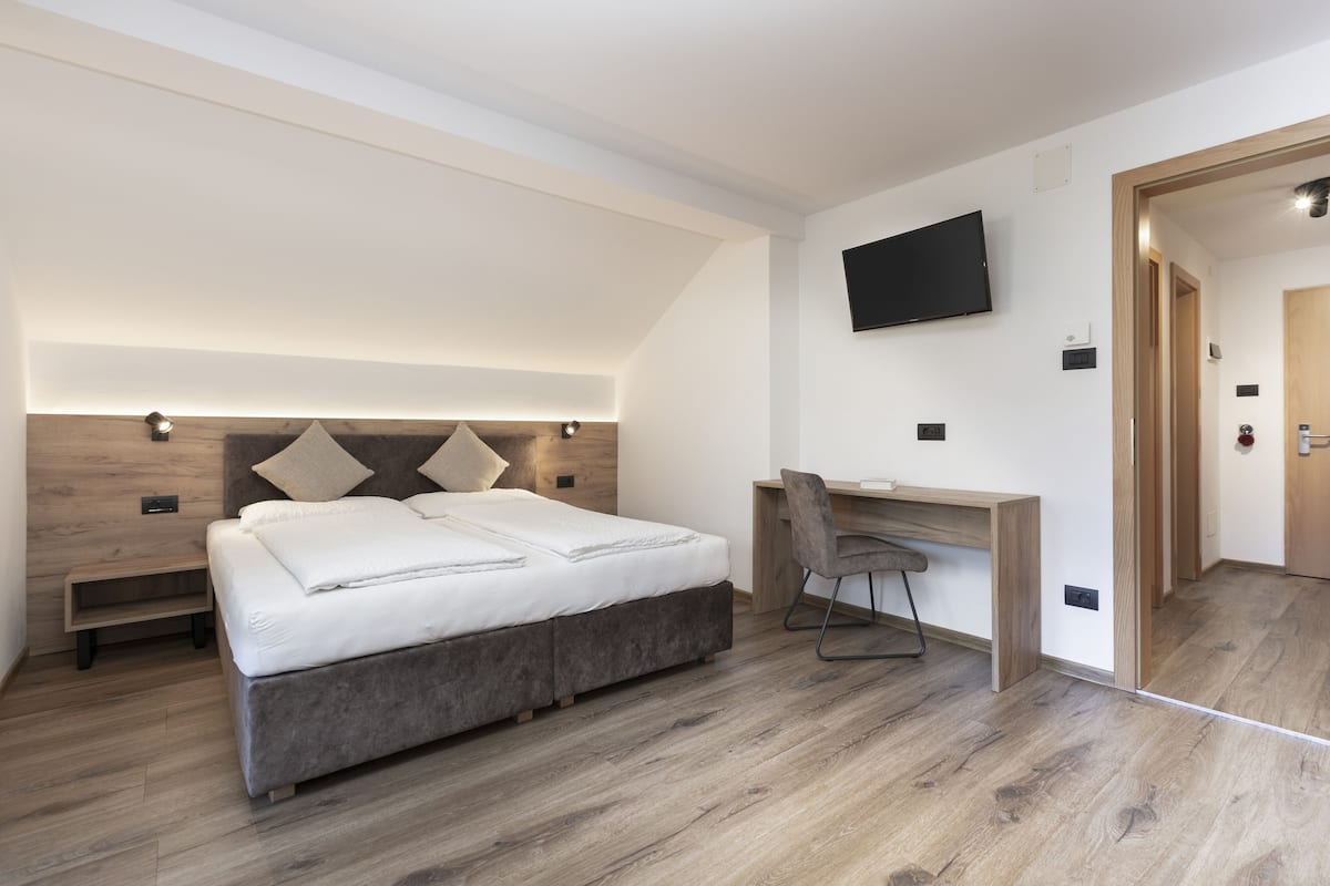 A modern bedroom with a bed, a desk, and a TV.