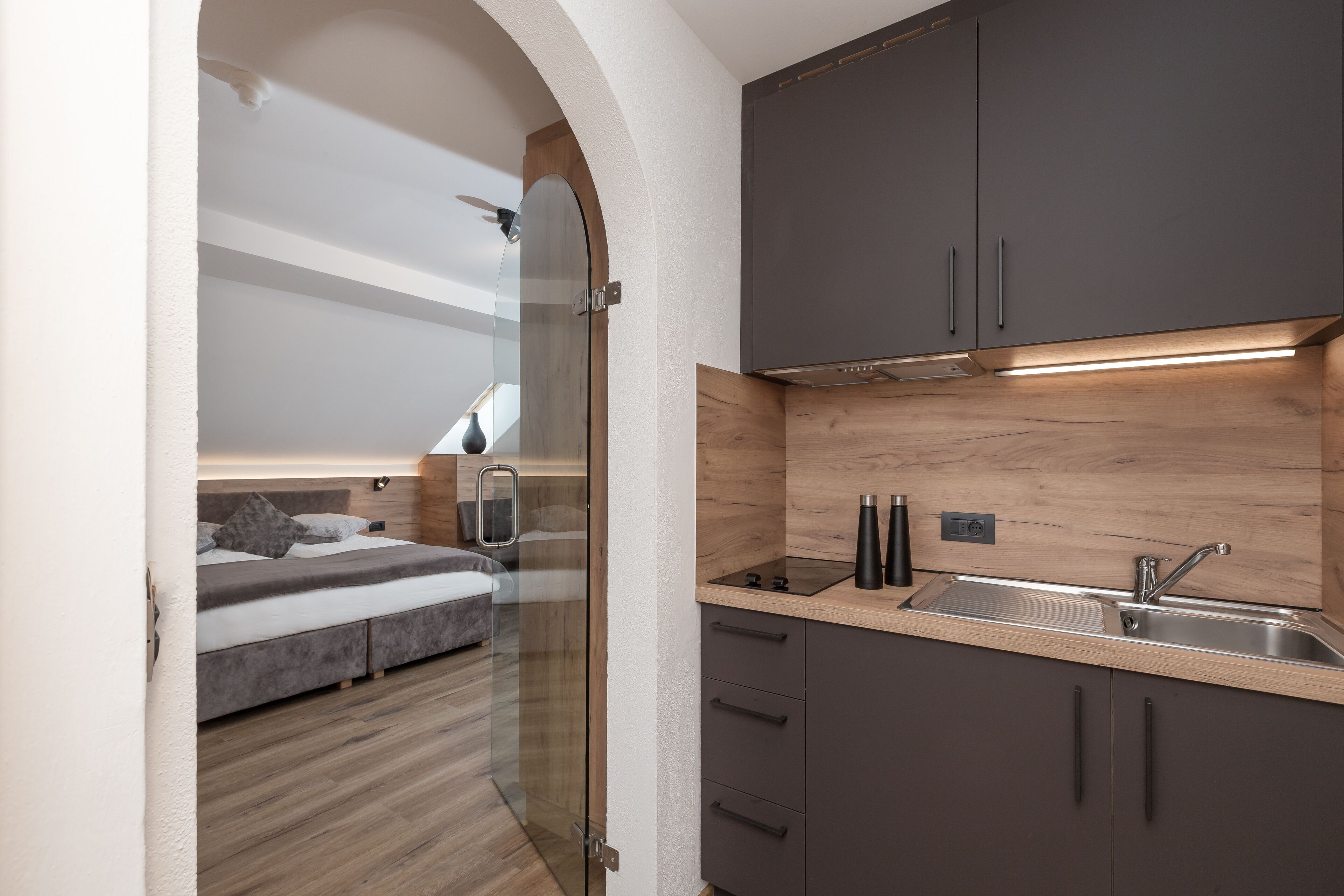 Una cocina moderna con armarios oscuros, encimera de madera y pileta de acero inoxidable.