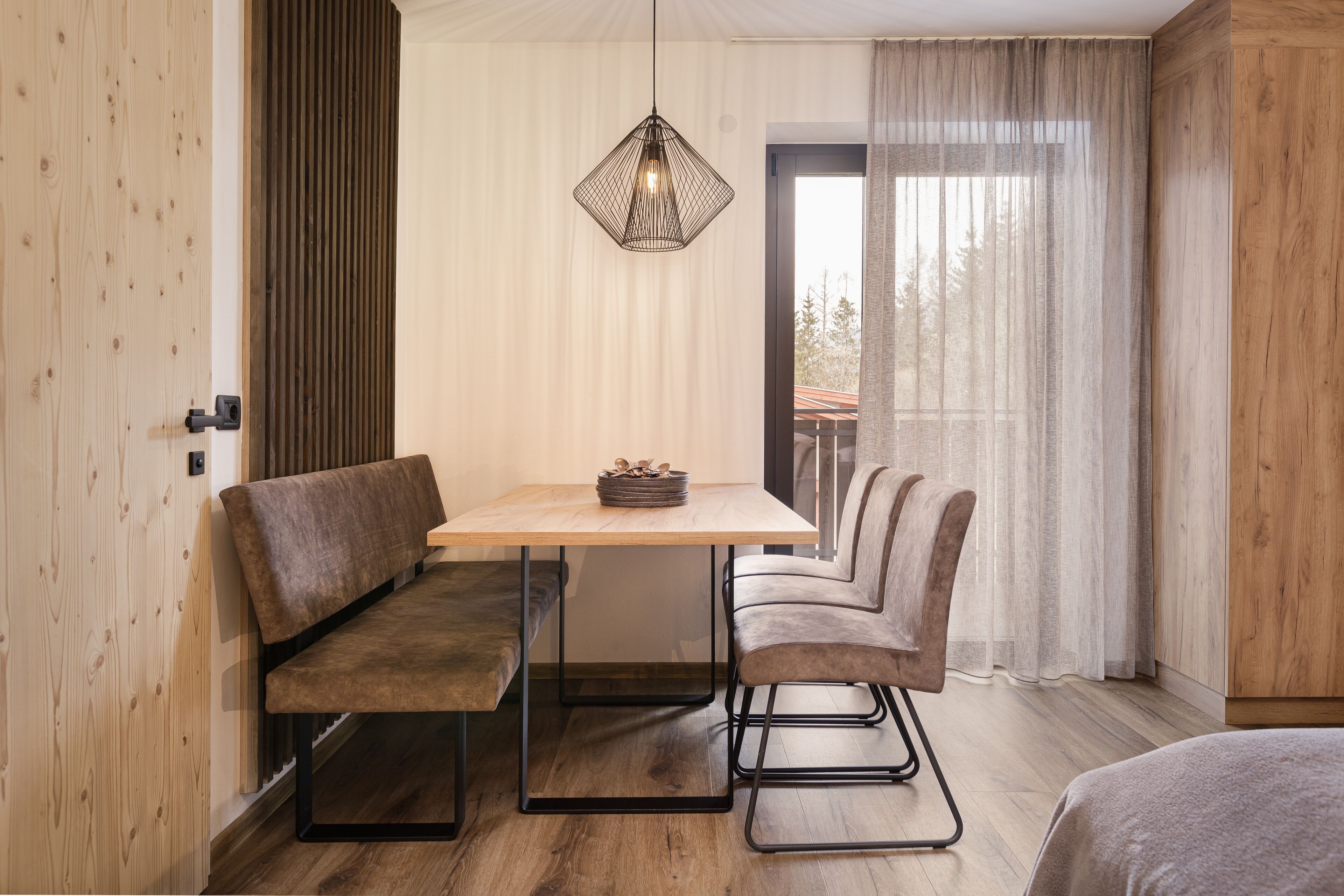 A cozy room with a wooden bench, a table, and a hanging light fixture.