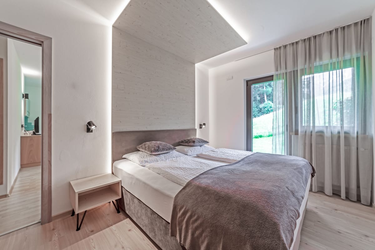A modern bedroom with a large bed, a bedside table, and a mirror.