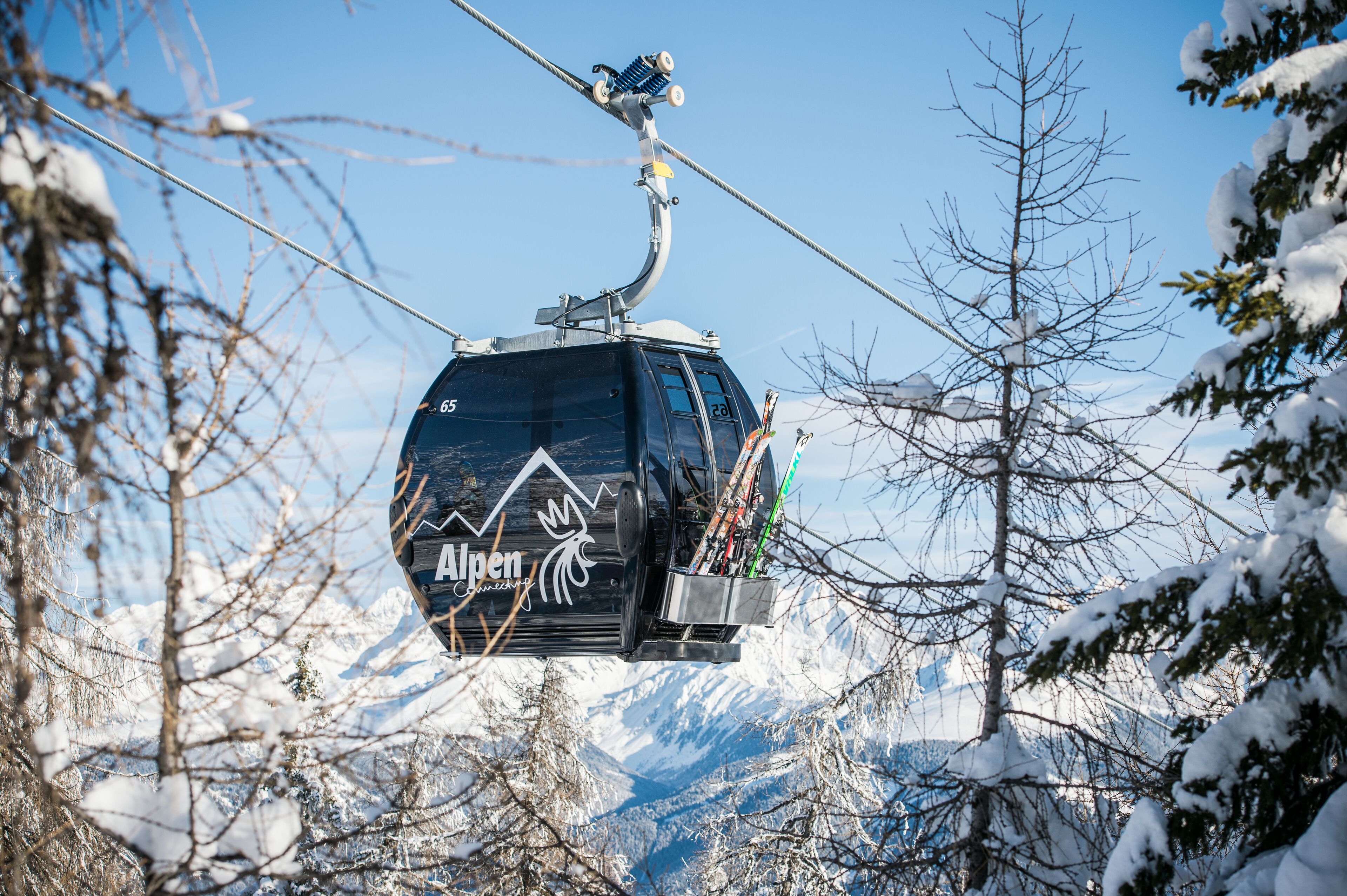 Silla de telesilla con el logotipo "Alpen" y una vista de montaña al fondo.