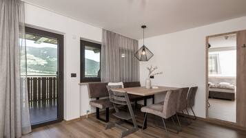 A modern dining area with a wooden table, cushioned chairs, and a pendant light.