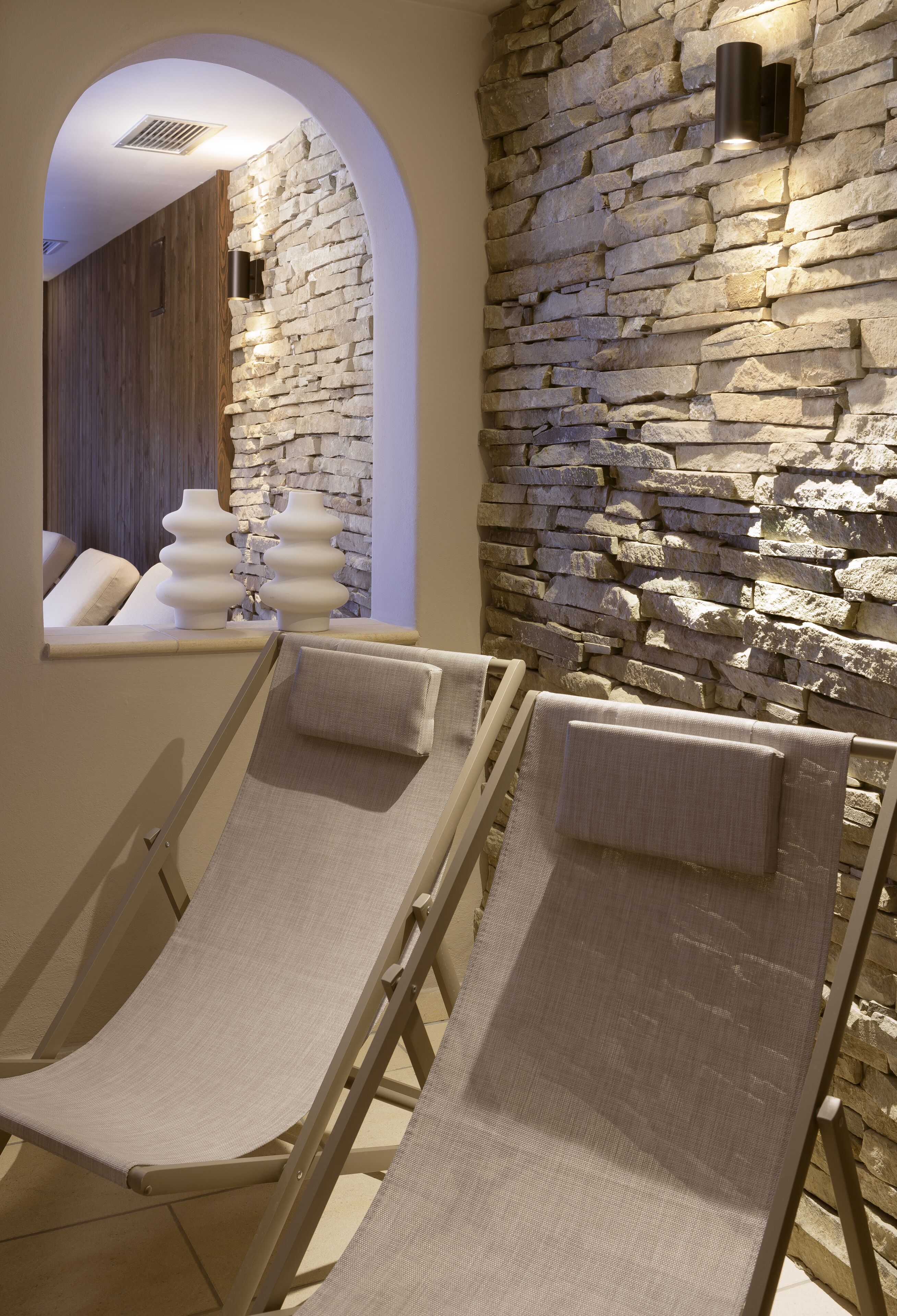 Un espace spa avec des murs en pierre et deux fauteuils inclinables.