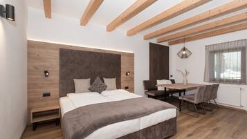 A modern bedroom with a large bed, wooden beams, a desk, and a window.