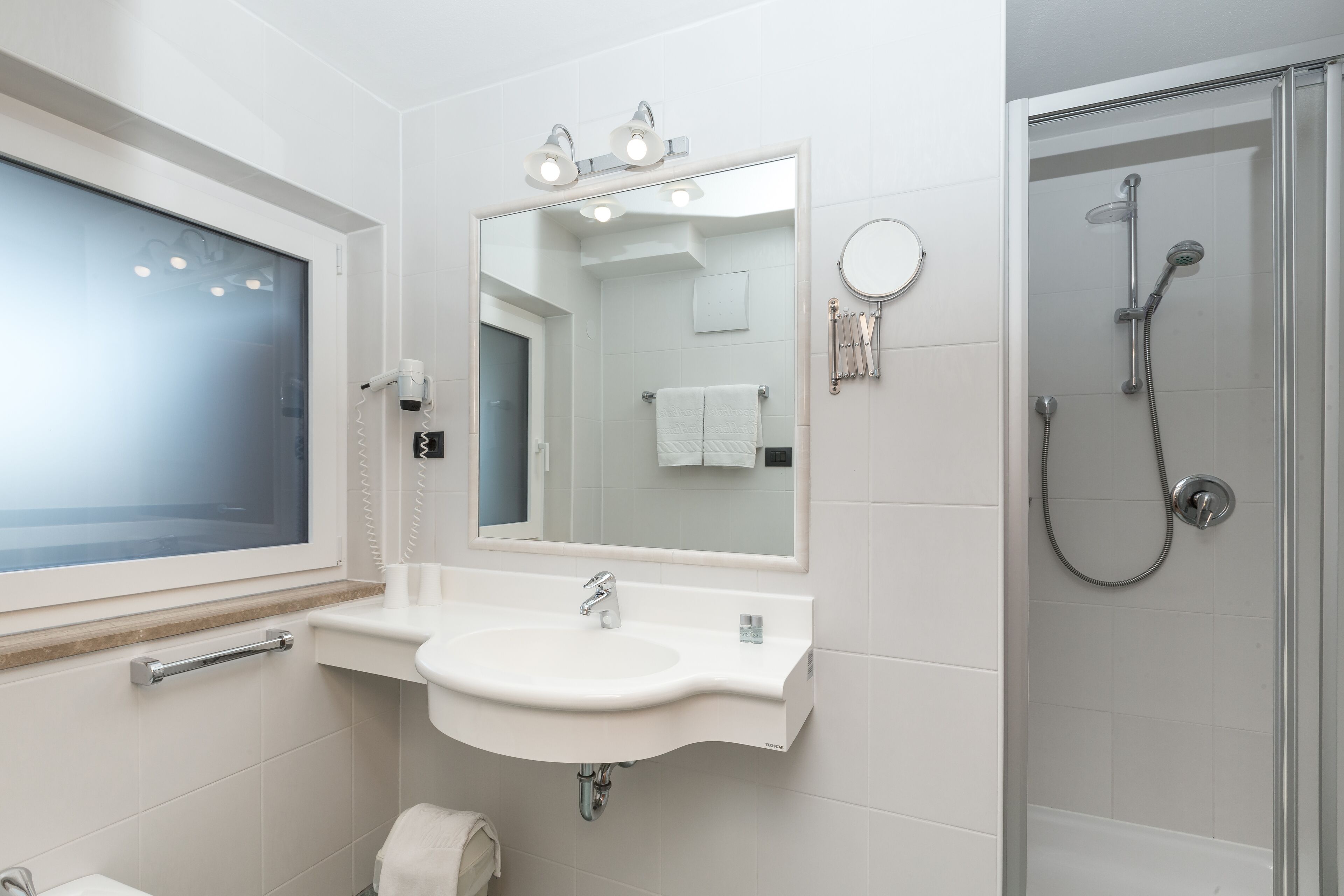 Un baño moderno con lavamanos, espejo y ducha.