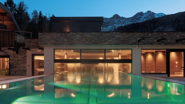 Ein modernes Gebäude mit Schwimmbad, Steinmauern und Bergblick.