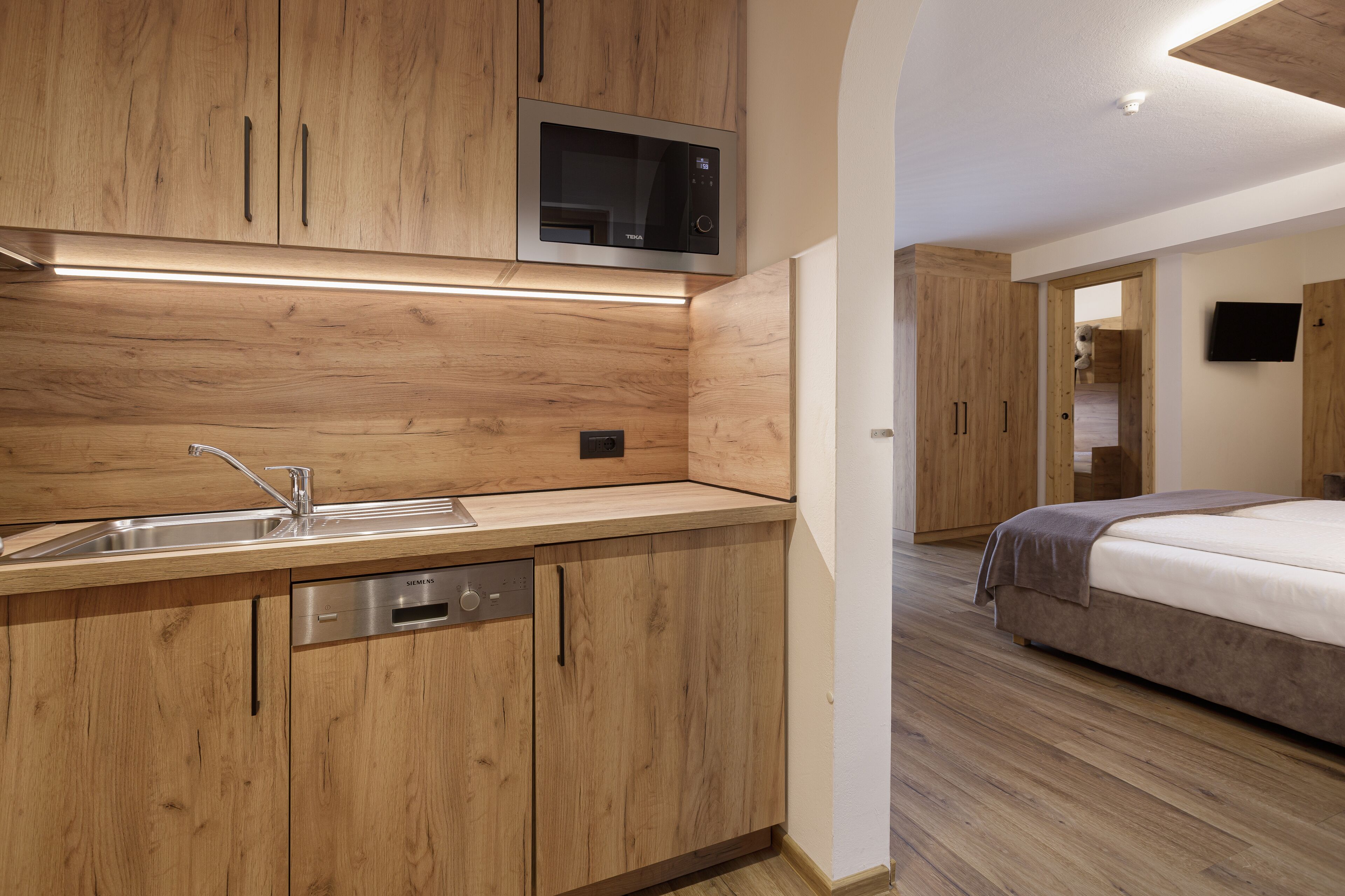A modern kitchen with wooden cabinetry, a built-in microwave, and a stainless steel dishwasher.
