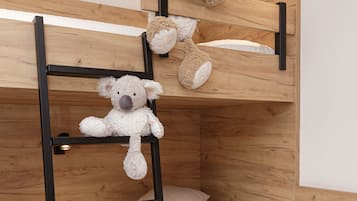 Una cama litera con dos osos de peluche, una mesita de noche y una lámpara de pared.