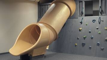 Un área de juegos con un tobogán y una pared de escalar.