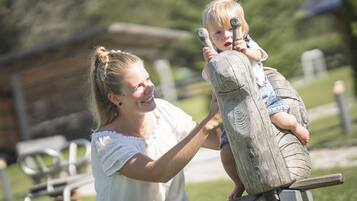 A person holding a child on a wooden swing.