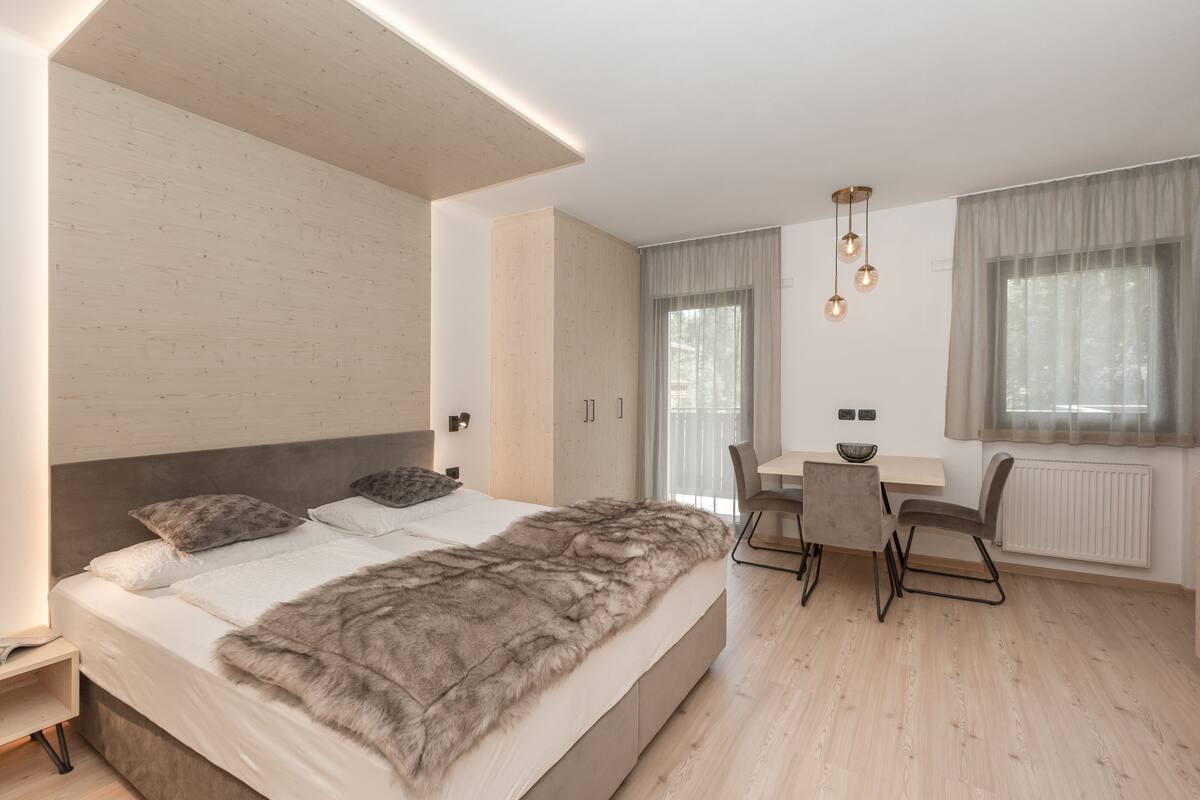 A modern bedroom with a large bed, a desk, and a chair.