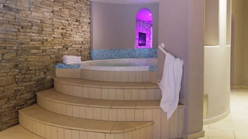 A spa area with a stone wall, a hot tub, and a small archway with purple lighting.