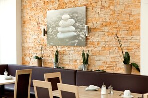 A restaurant with stone walls, a painting of stacked stones, and potted plants. - Berghof Graml (Hallwang)