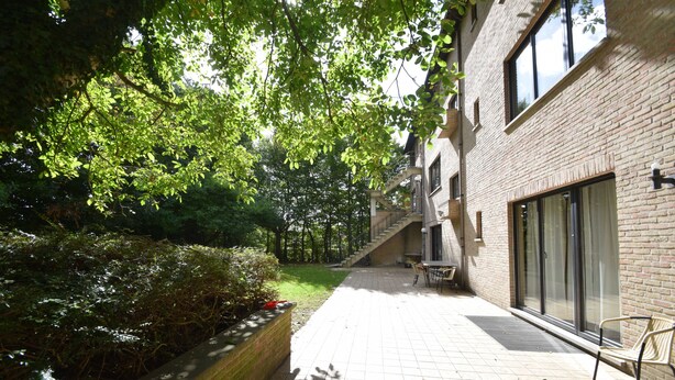 A courtyard with a brick building, a bench, and a small table. - Budget Flats Brussels (Brussels)