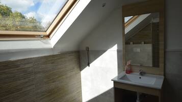 Une lucarne dans une salle de bain avec un meuble-lavabo en bois et un miroir.