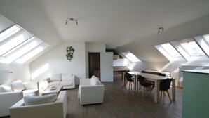 A spacious living area with a dining table and chairs, a sofa, and a kitchen in the background. - Budget Flats Brussels (Brussels)