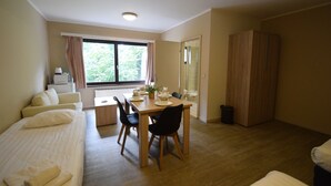 A room with a bed, a dining table with chairs, a window with curtains, and a wardrobe. - Budget Flats Brussels (Brussels)