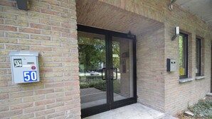 A brick building with a glass door entrance, a parking meter, and a mailbox. - Budget Flats Brussels (Brussels)