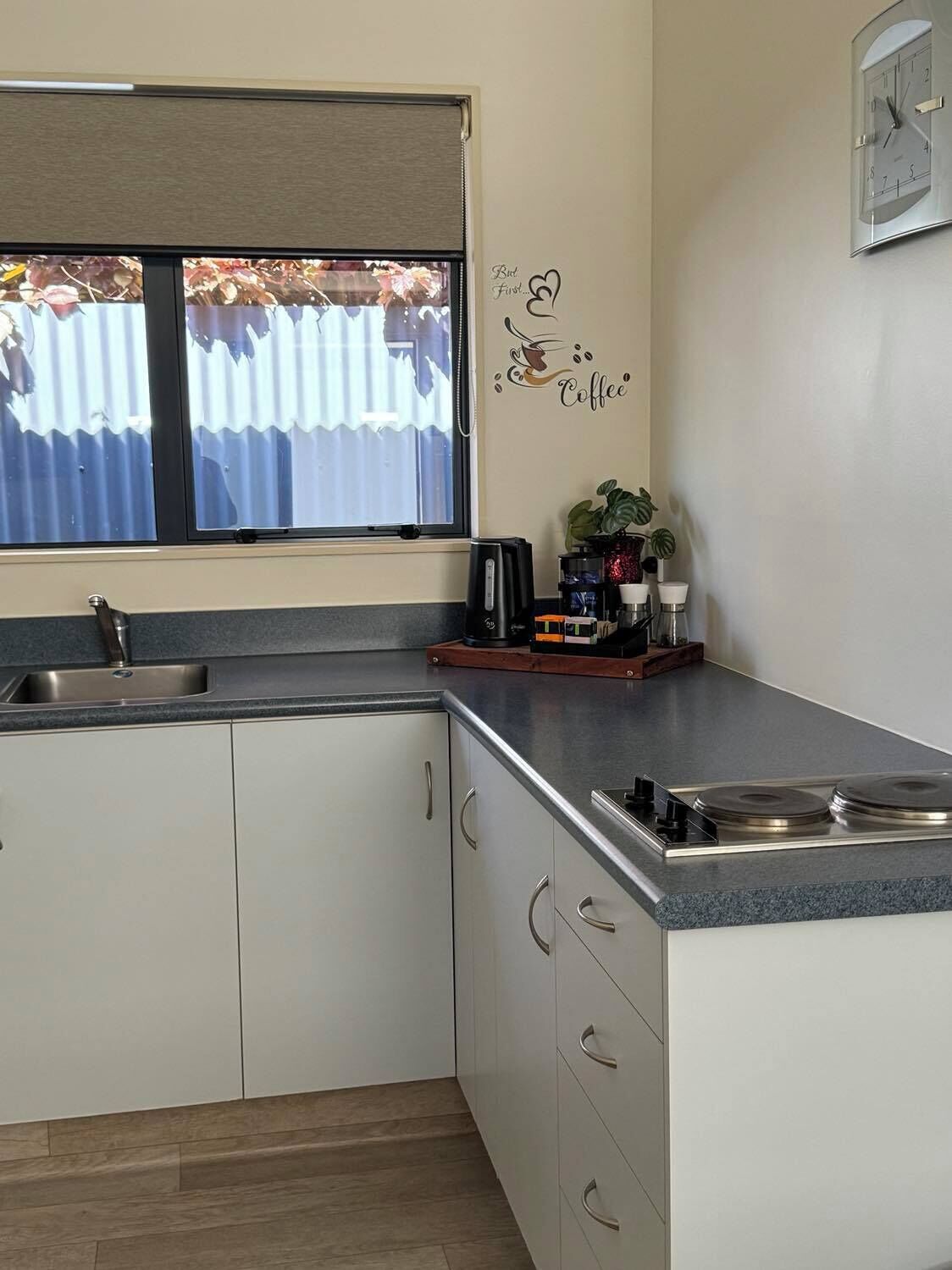 Une cuisine équipée d’une cuisinière intégrée, d’un évier et d’une fenêtre donnant sur un jardin.