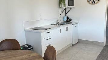A modern kitchen with white cabinets, a microwave, and a clock on the wall.